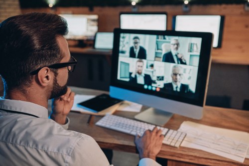 Confident,Young,Man,Having,Video,Conference,With,The,Colleagues,While Confident,Young,Man,Having,Video,Conference,With,The,Colleagues,While