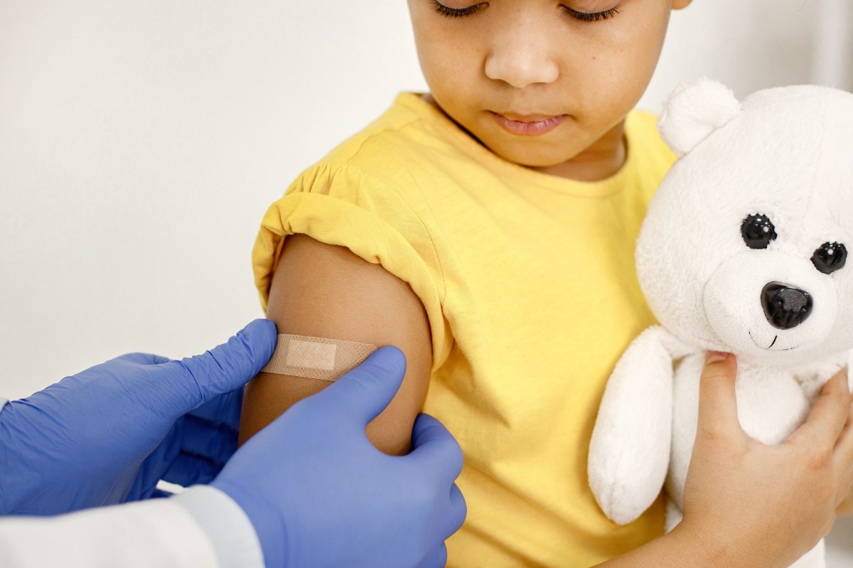 Doctor stick a band-aid on a girl's shoulder after a vaccination