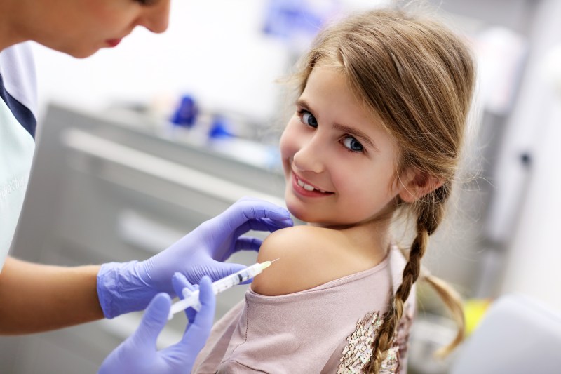 Picture of brave little girl receiving injection or vaccine with a smile